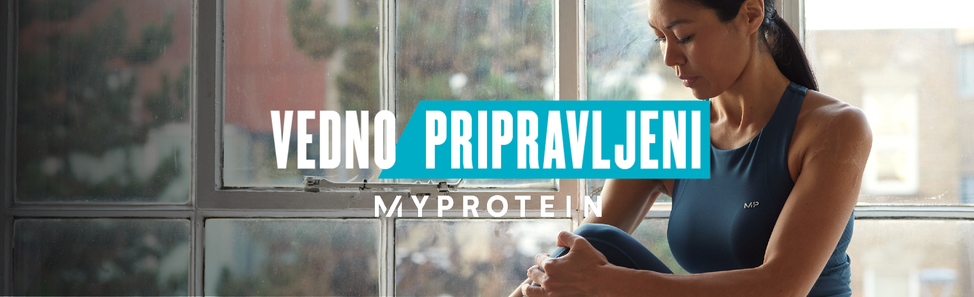 A woman wearing MP gym clothing sat on a window ledge stretching with the text 'You're Already Ready - MYPROTEIN' overlaying the image.